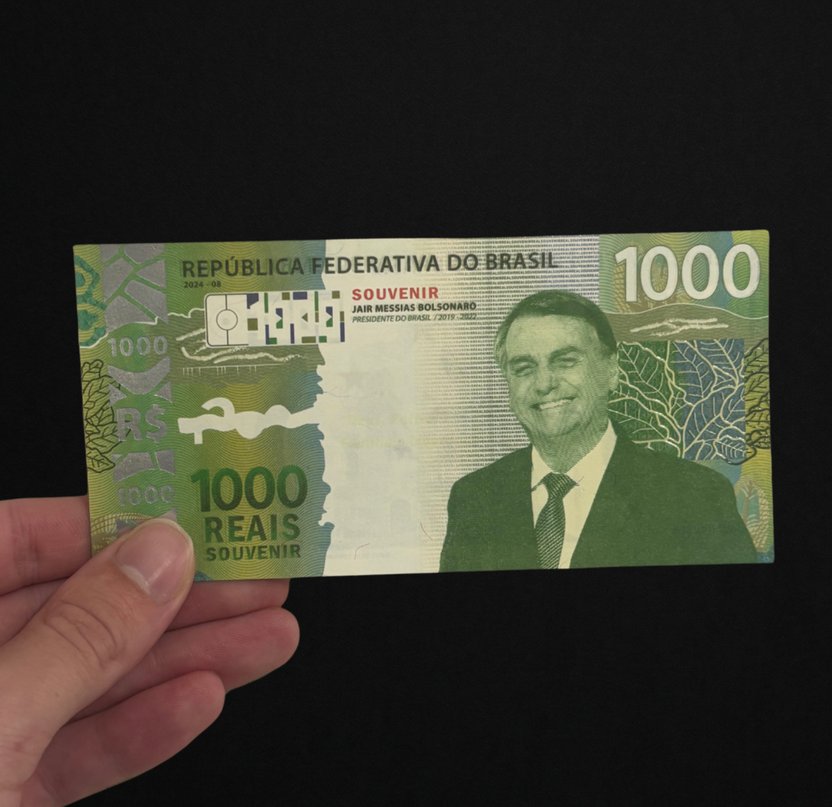 Cédula Colecionável Bolsonaro segurada pela ponta, mostrando que não dobra sozinha