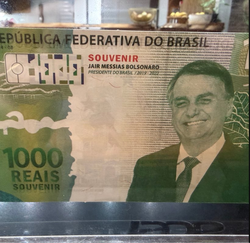 Cédula Colecionável Bolsonaro contra a luz, revelando a marca d'água na área clara do papel